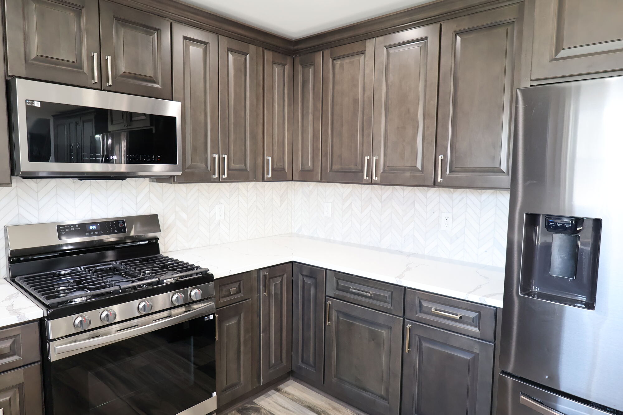 Corner kitchen layout with stainless refrigerator and stylish backsplash in a Schererville custom home by Clear Contractors.