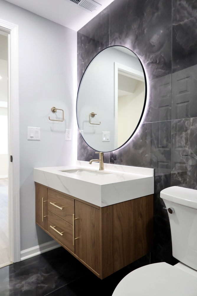 Custom bathroom vanity with round LED mirror and gold fixtures by Clear Contractors in Crown Point, IN.