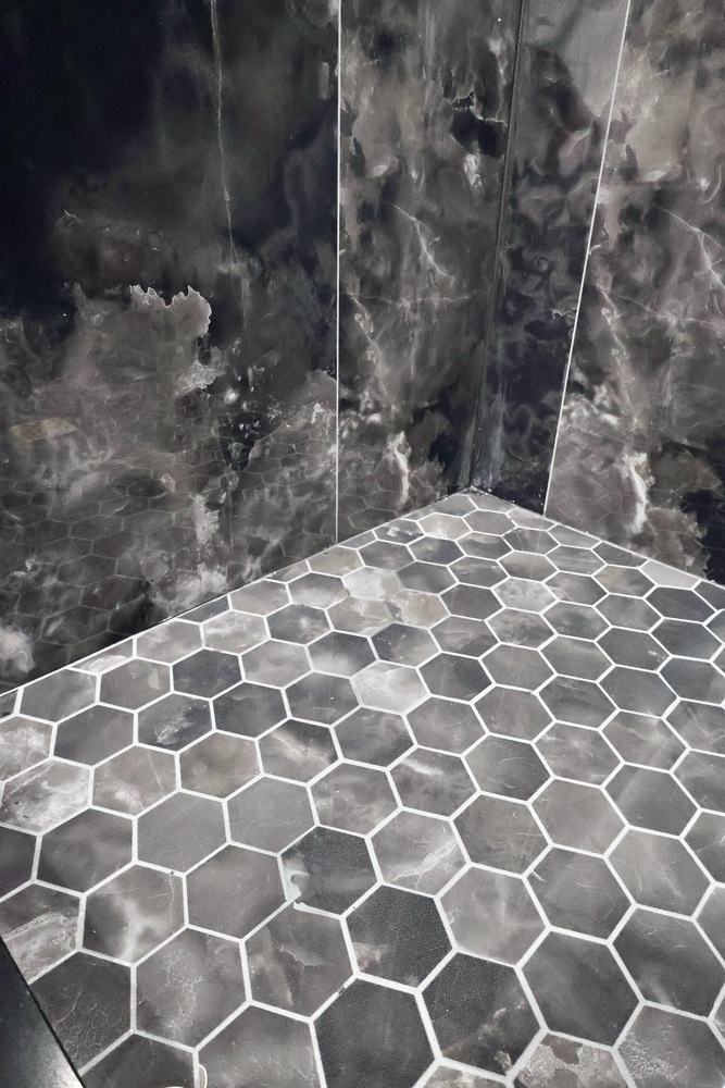Hexagonal black shower floor tile in custom home bathroom by Clear Contractors in Crown Point, IN.