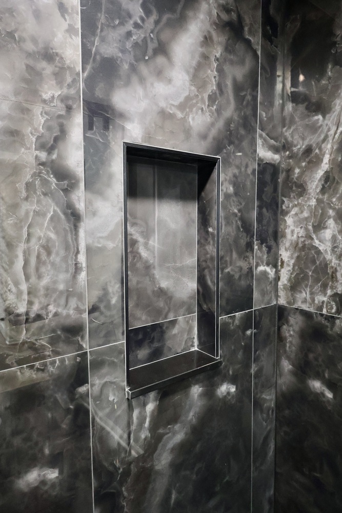 Modern shower inset for storage within dark tile surround in a custom home by Clear Contractors.