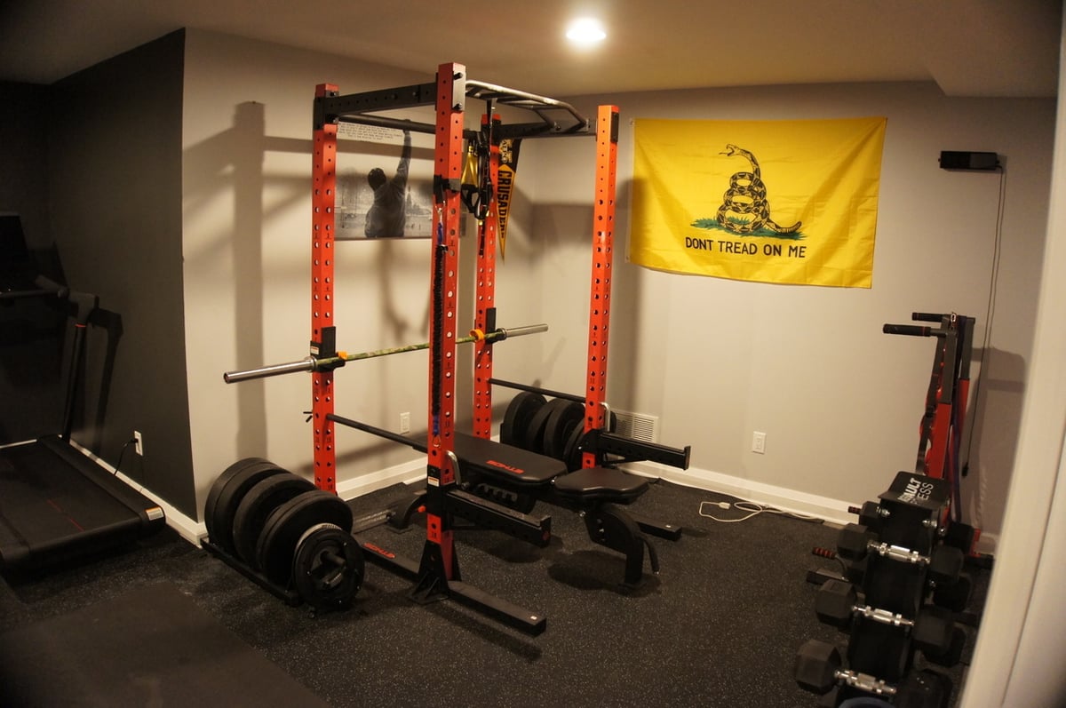 Basement fitness area featuring squat rack and free weights for Basement + Bathroom Remodel in St. John