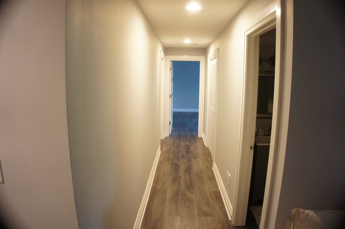 Long basement hallway with wood-look flooring for Basement + Bathroom Remodel in St. John