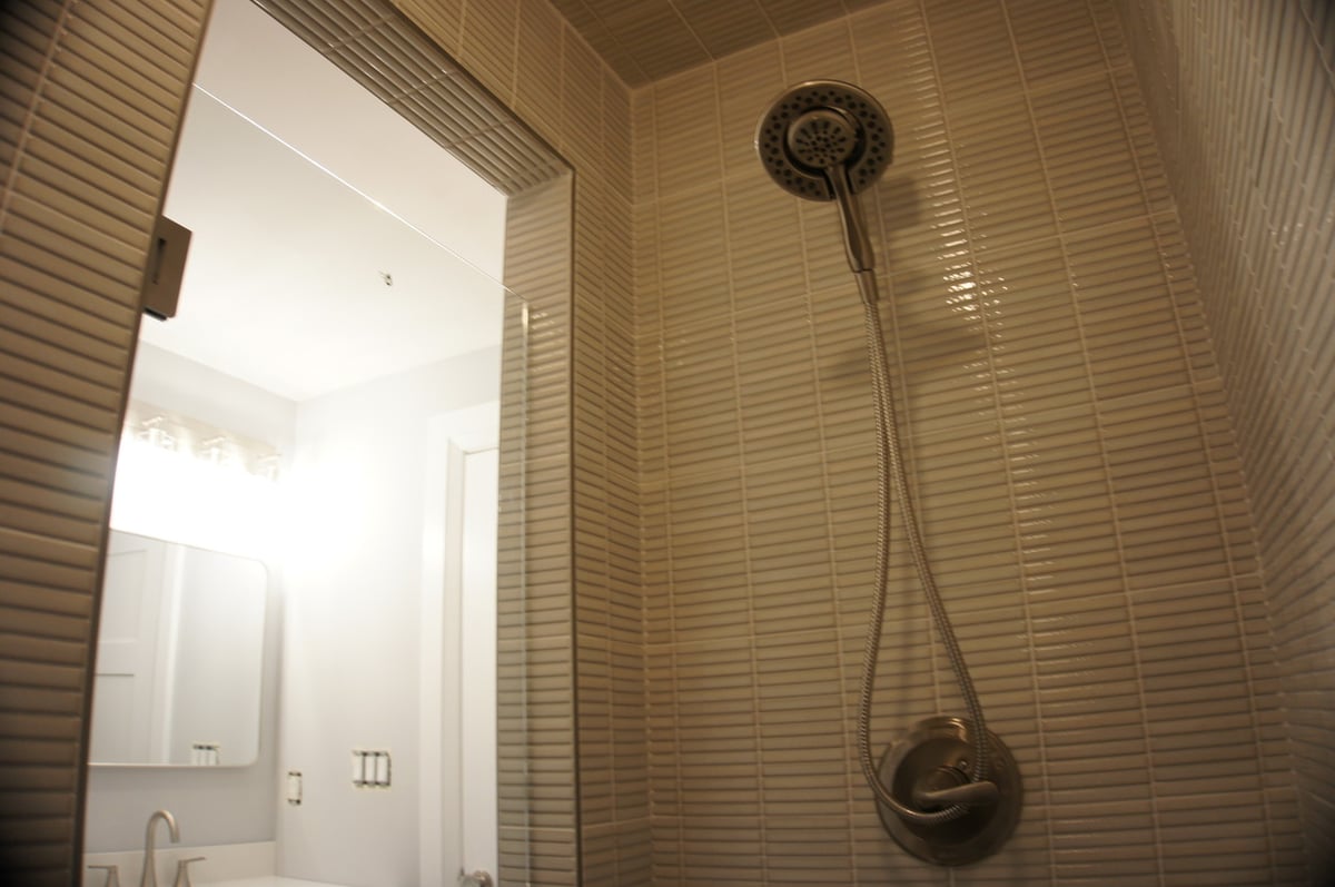 Showerhead and tiled wall in basement bathroom for Basement + Bathroom Remodel in St. John