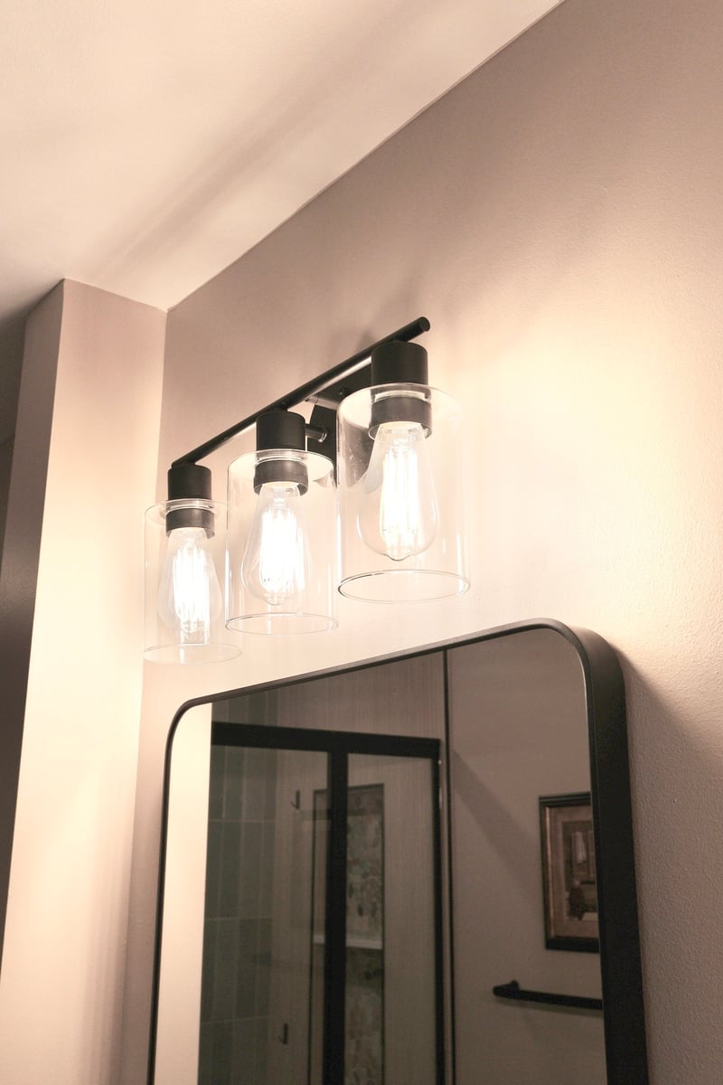 Bathroom remodel in Lowell featuring a modern black vanity light with clear glass shades