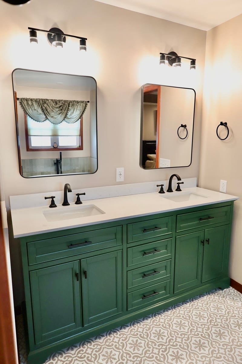 Bathroom remodel in Lowell featuring green double vanity and black framed mirrors