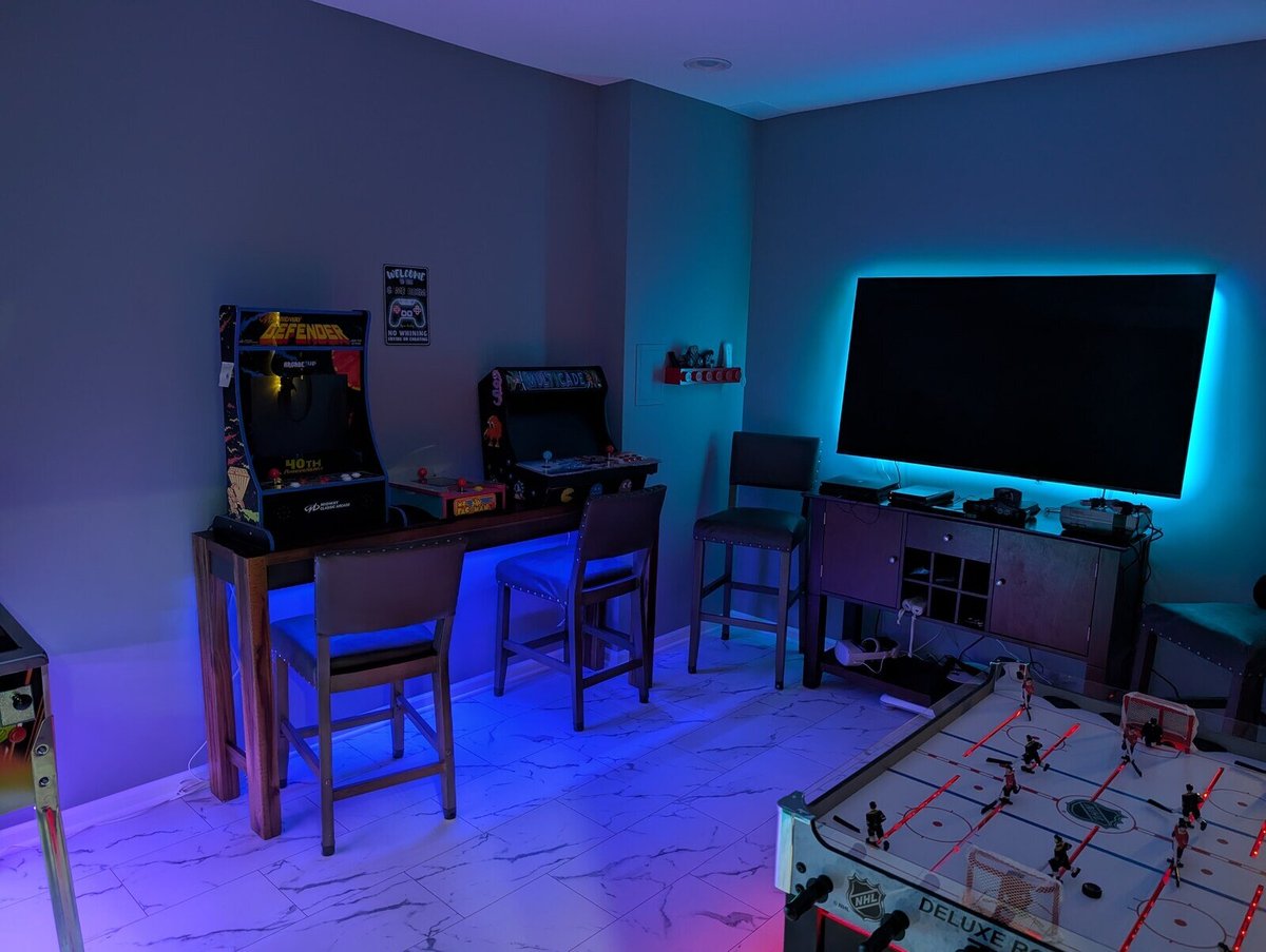 Basement game room featuring retro arcade games, colorful lighting, and a TV, remodeled by Clear Contractors in Northwest Indiana