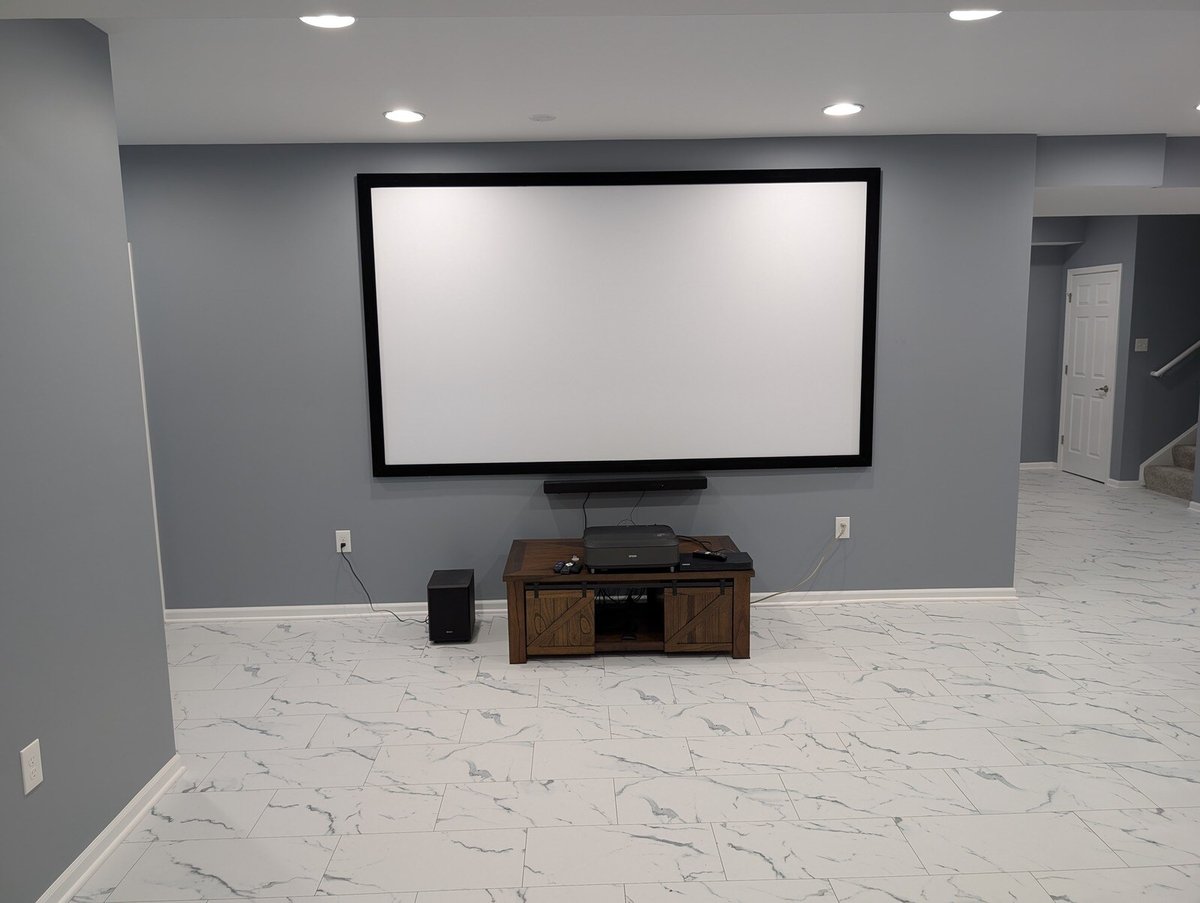 Basement media room with a large projector screen and modern flooring by Clear Contractors in Northwest Indiana