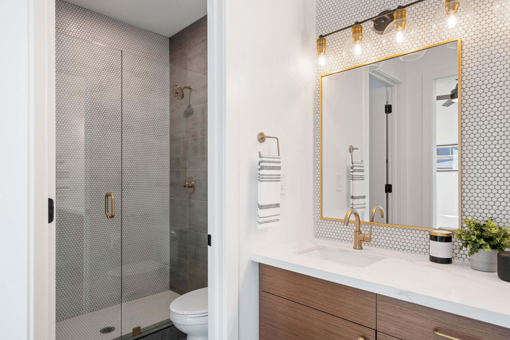 Contemporary bathroom with golden accents and a glass shower door remodeled by Clear Contractors in Northwest Indiana