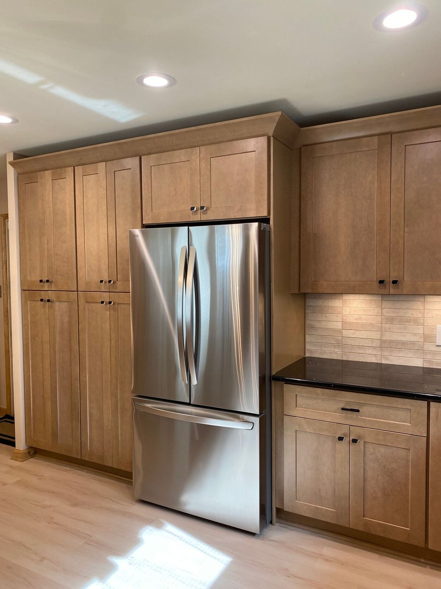 Stainless steel French-door refrigerator next to wood cabinetry in a kitchen remodel in Lynwood by Clear Contractors