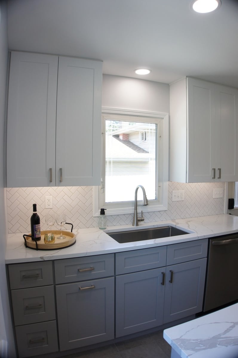 Kitchen sink area with white quartz counters and herringbone backsplash for Kitchen Remodel in Munster