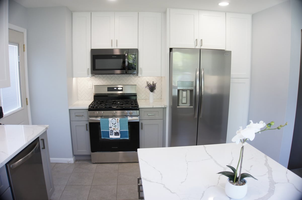 Stainless steel oven and fridge framed by white upper cabinets for Kitchen Remodel in Munster