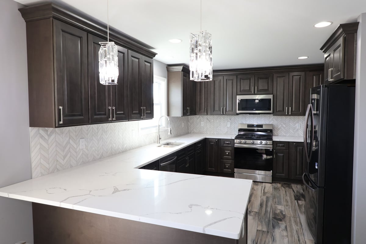 Close-up view of custom kitchen showcasing marble-look quartz counters and pendant lighting in a Schererville home by Clear Contractors.