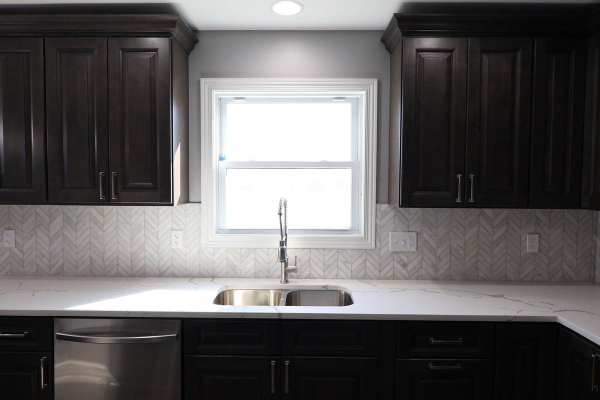 Kitchen sink area with large window and chevron backsplash in a custom home by Clear Contractors in Schererville.