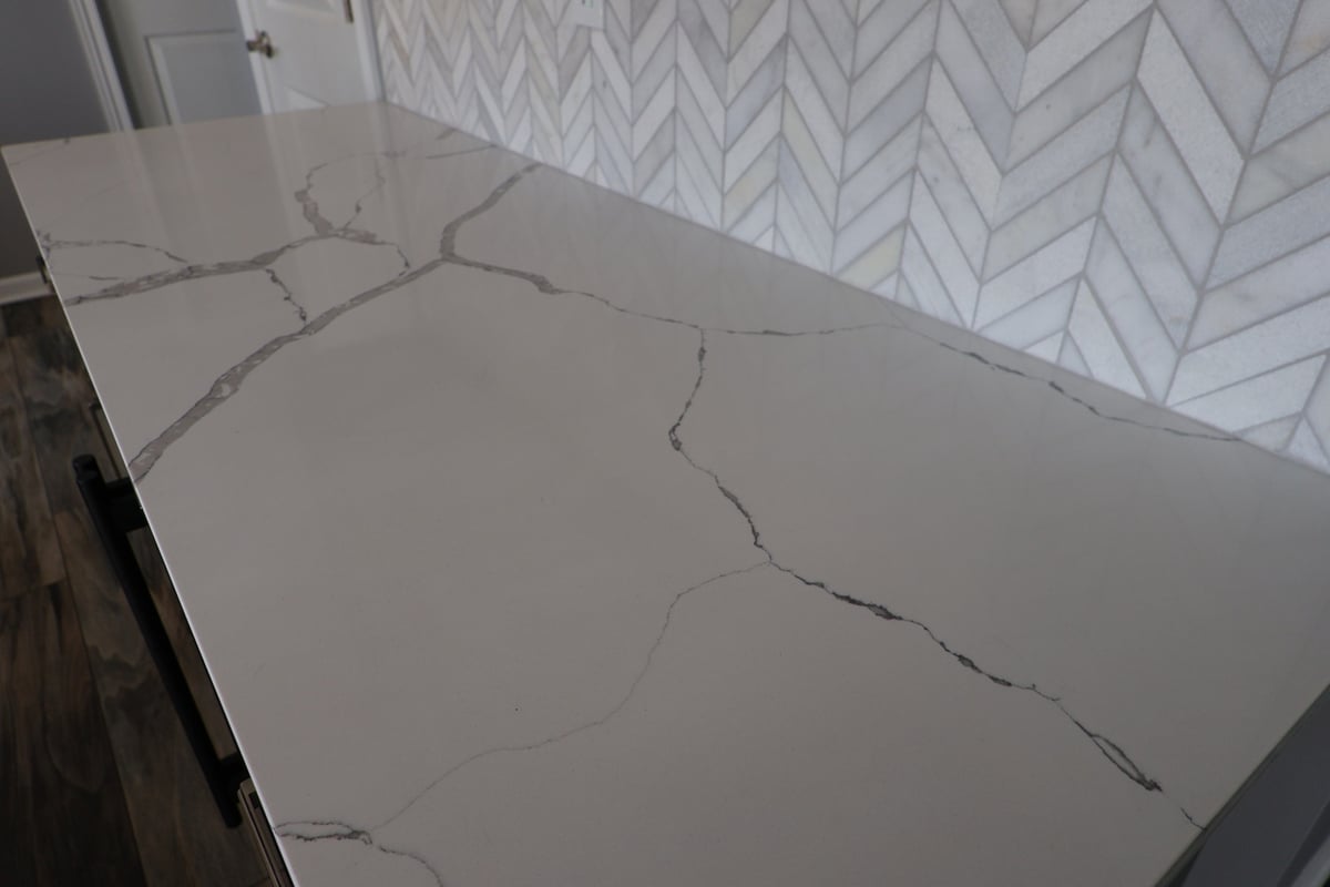 Quartz countertop against marble chevron backsplash in a custom Schererville kitchen by Clear Contractors.