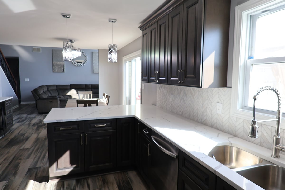 U-shaped kitchen island with quartz countertops and dark wood cabinets in a Clear Contractors home in Schererville.